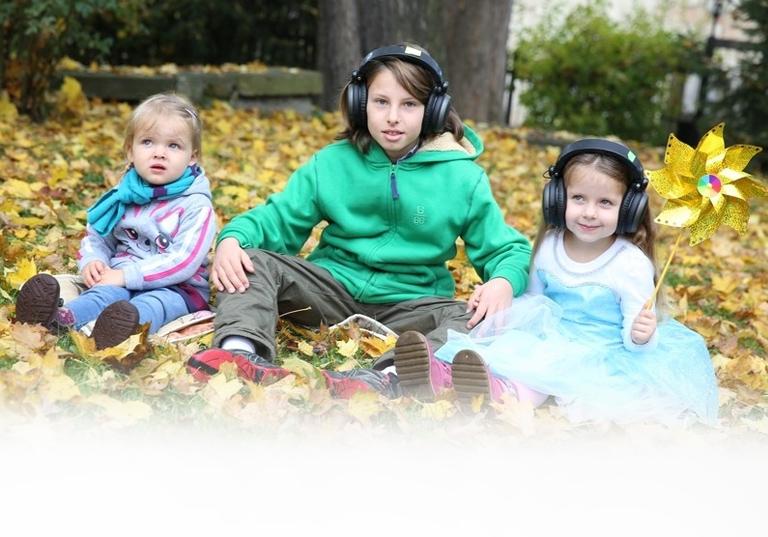 dzieci w słuchawkach siedzące na liściach